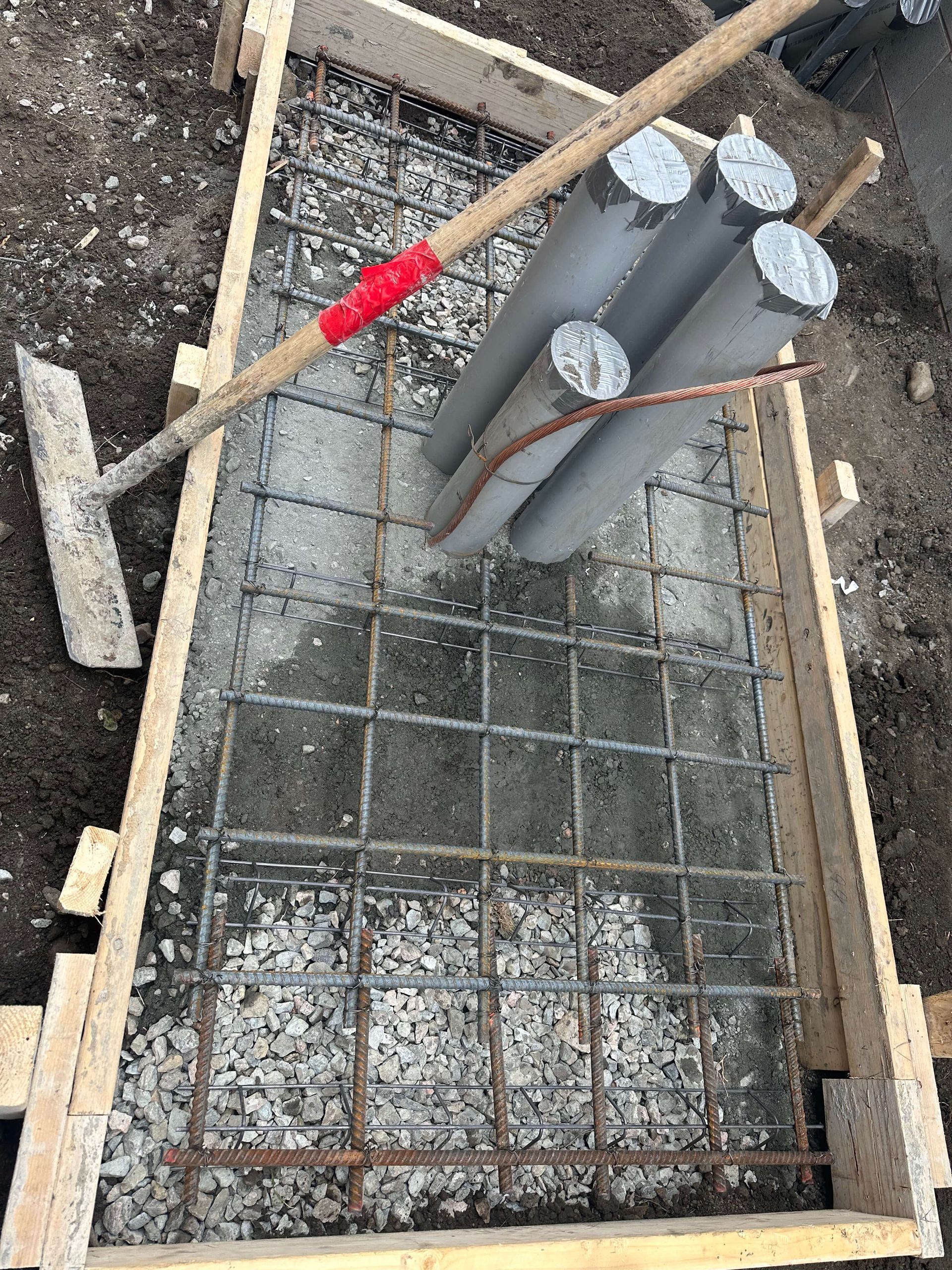 A wooden box filled with concrete and a shovel.