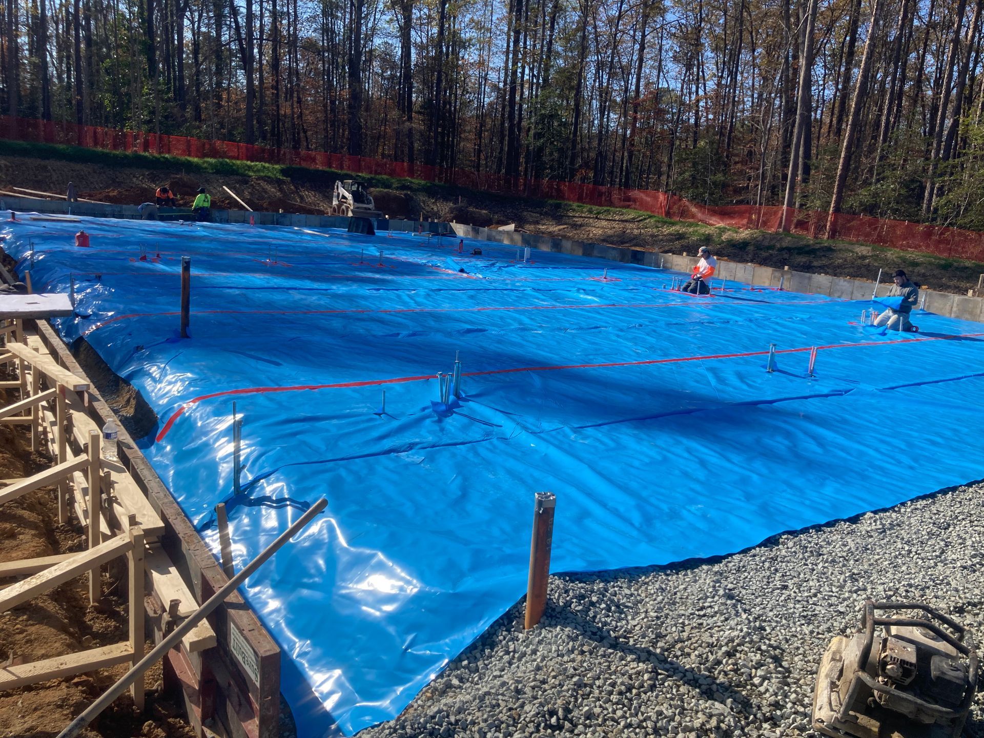 Construction workers on a site laying asphalt, wearing safety vests and helmets.