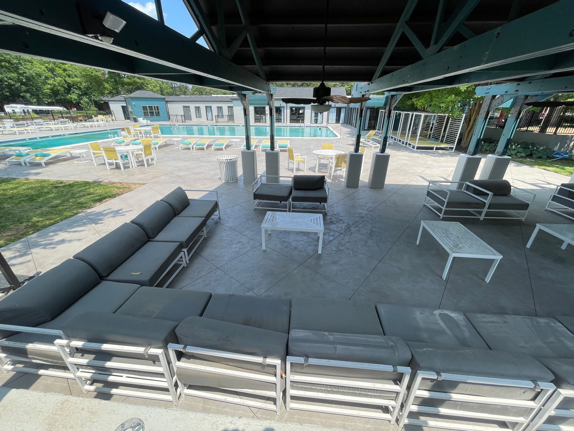 A patio with a lot of furniture and a pool in the background