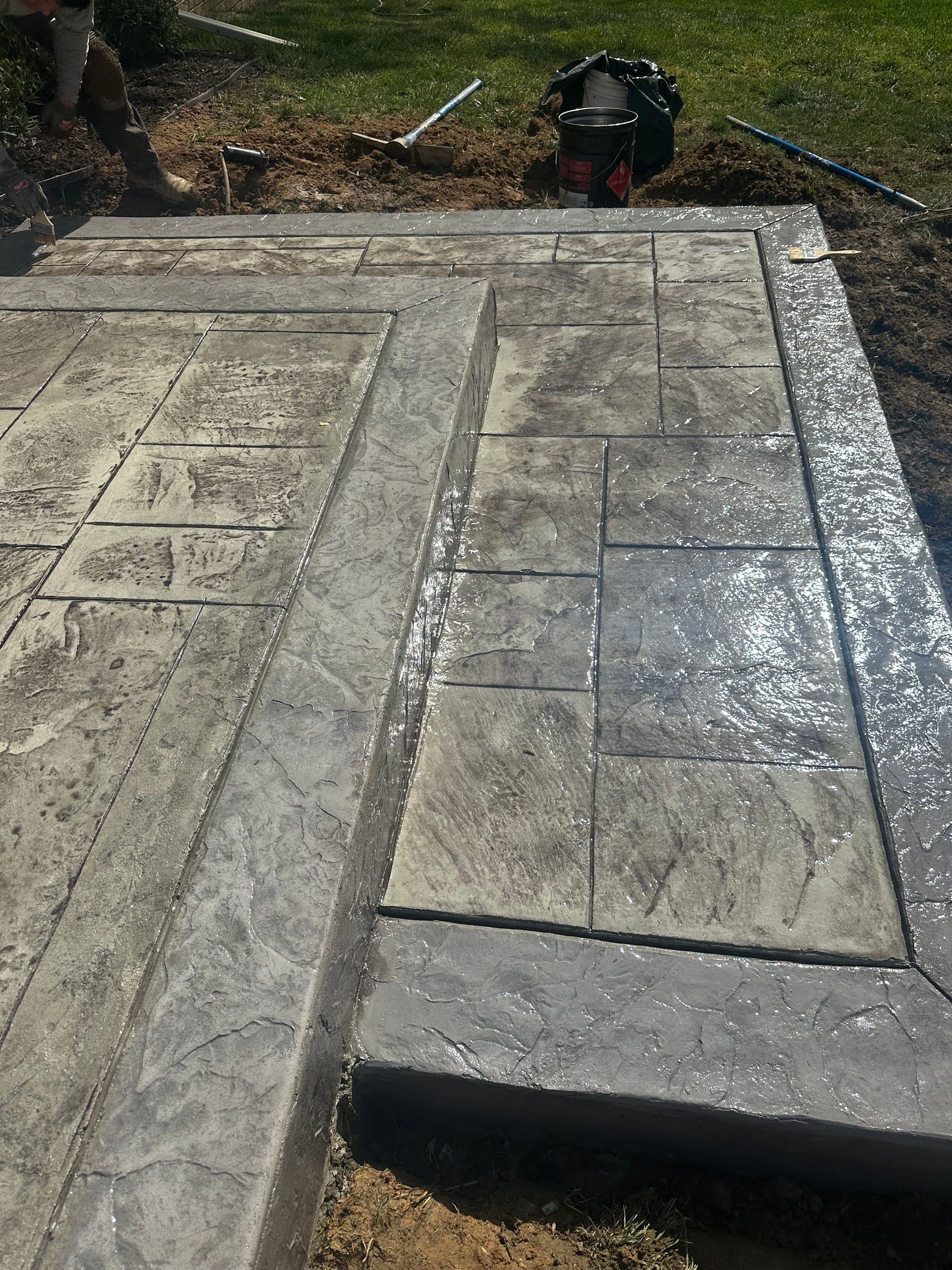 A concrete walkway is being built in a backyard