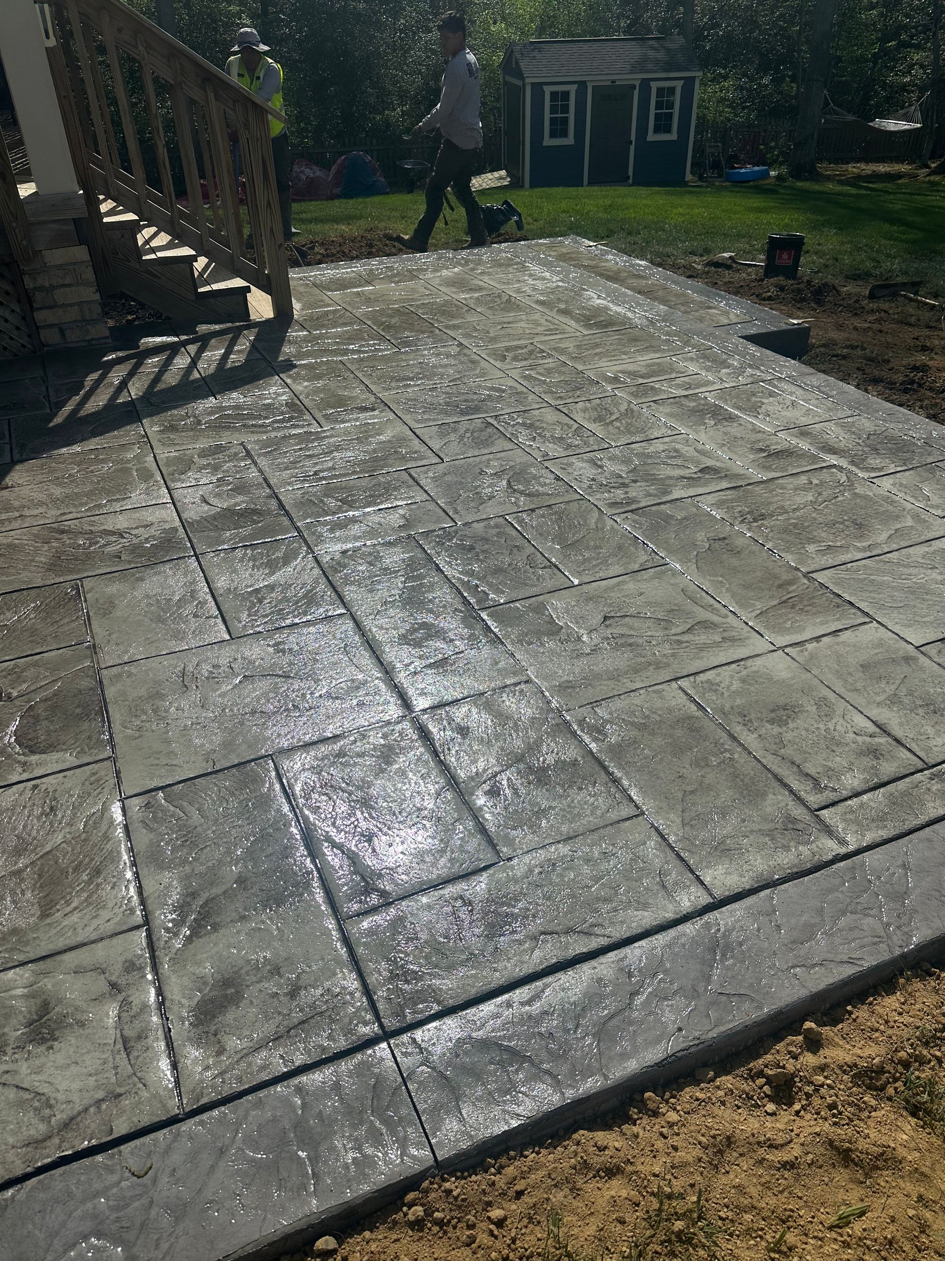 A man is walking on a concrete patio in front of a house.