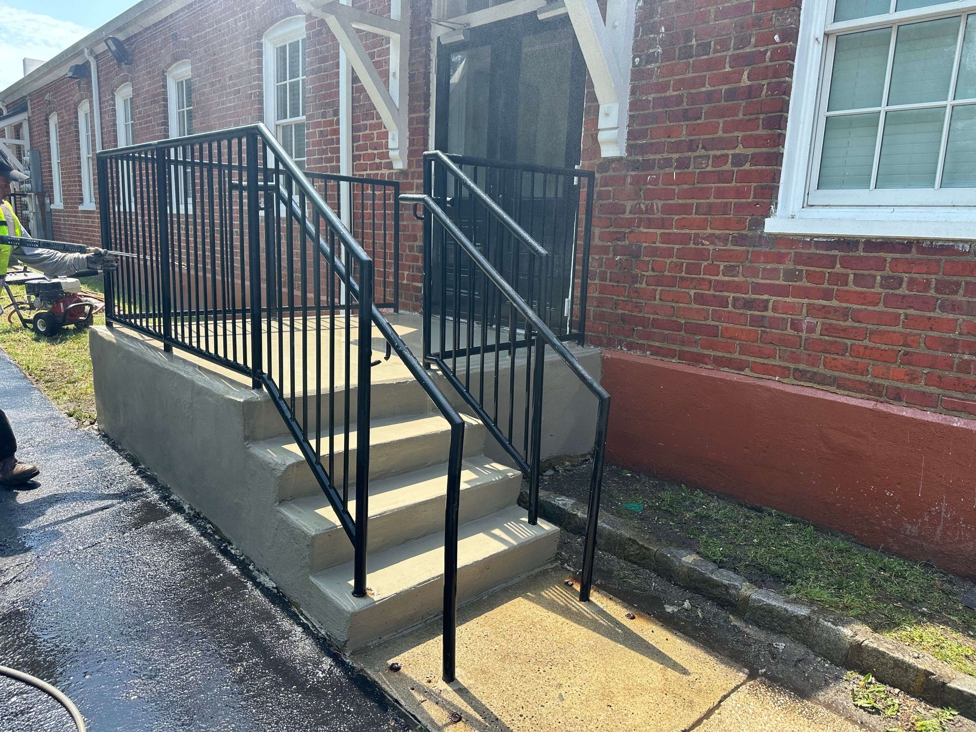 A set of stairs leading up to a brick building with a metal railing.