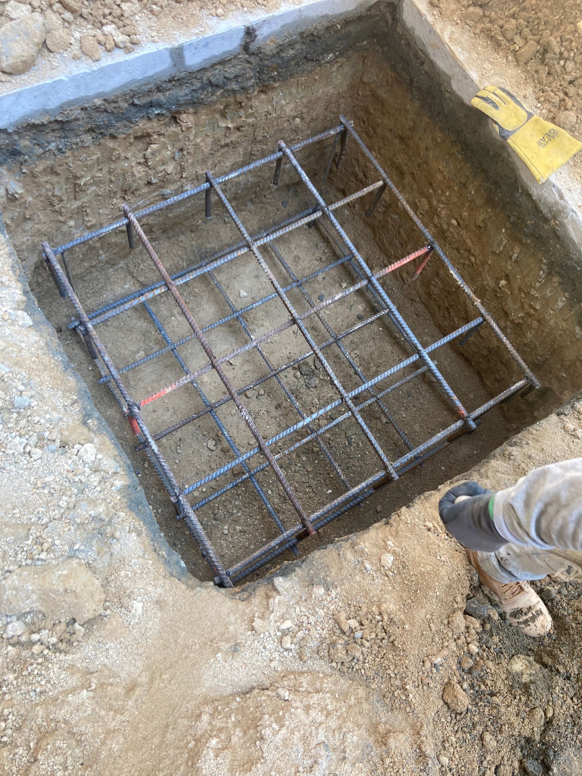 A person is standing in a hole with a metal frame in it.