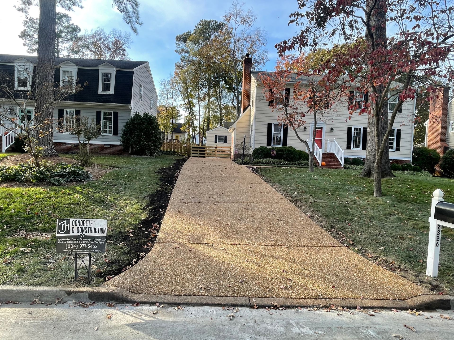 A driveway leading to a house with a sign on the side of it.