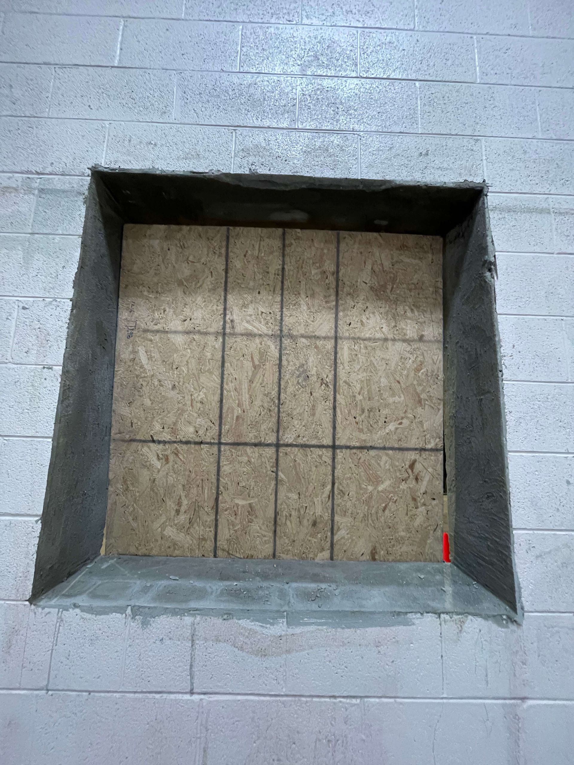 A square hole in a brick wall with a tile floor in it.