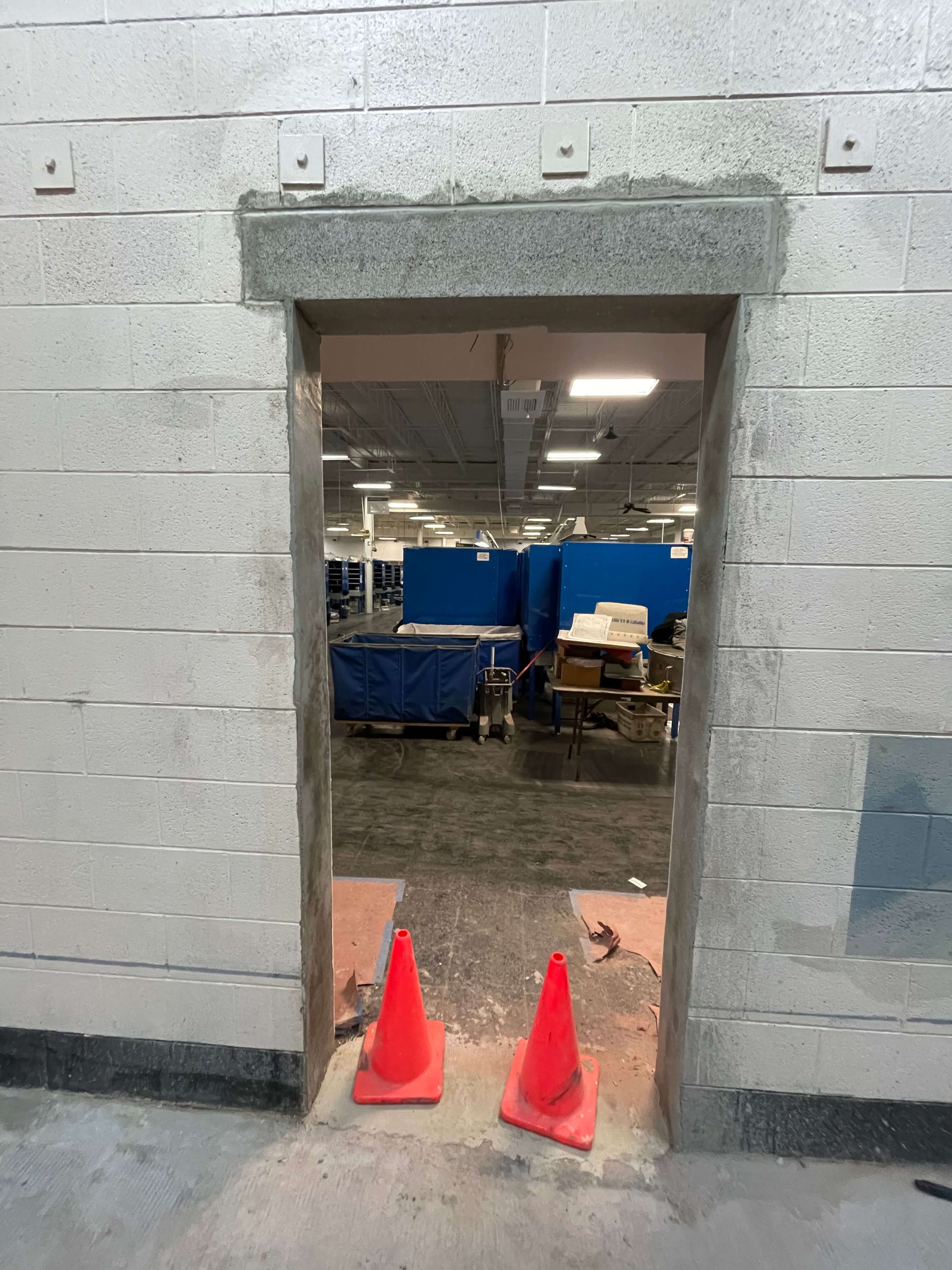 Two orange cones are sitting in front of a brick wall.