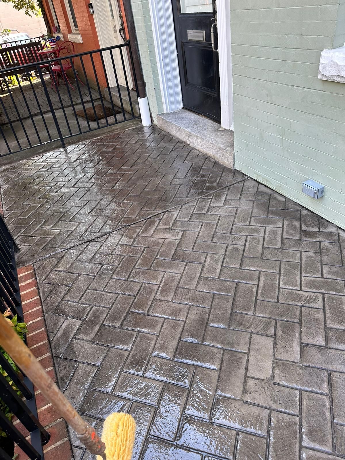 A person is cleaning a brick patio with a broom.