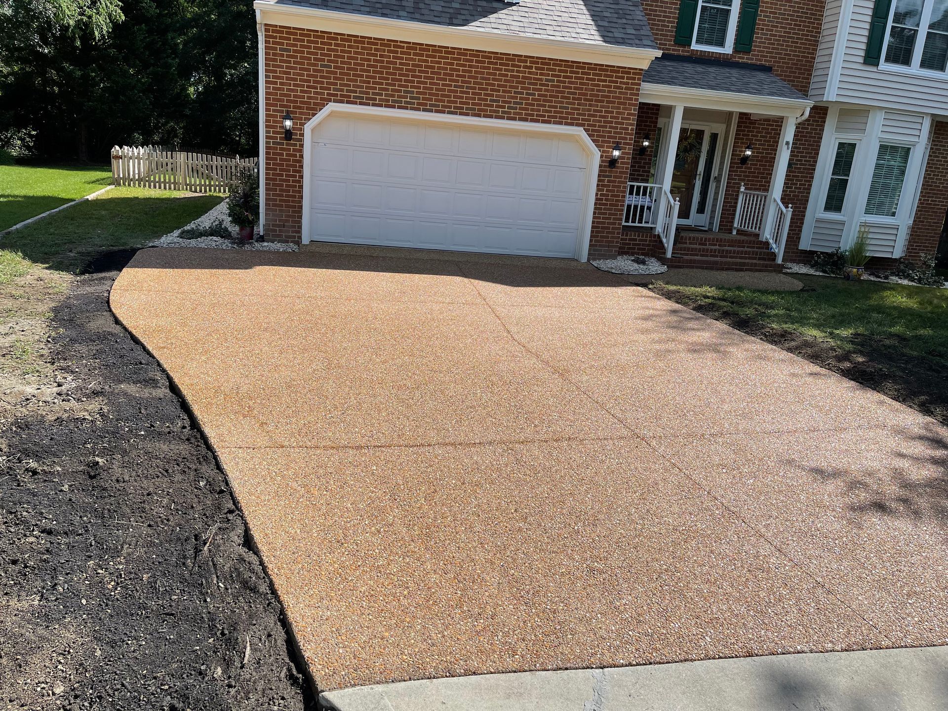 A brick house with a concrete driveway in front of it.