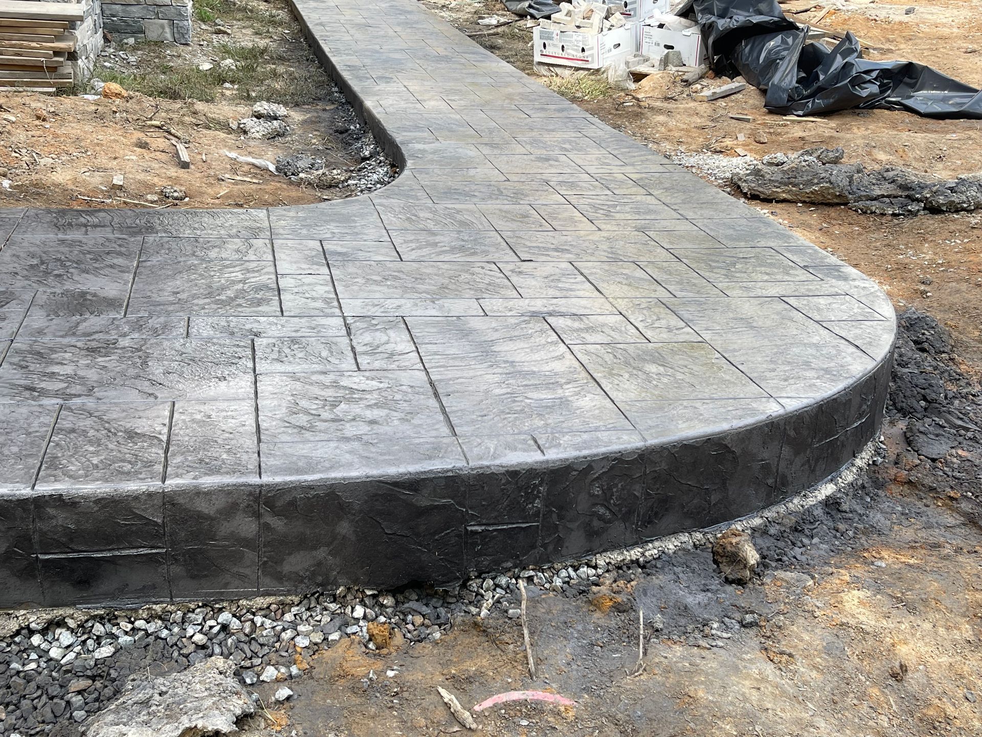 A concrete walkway is being built in the dirt.