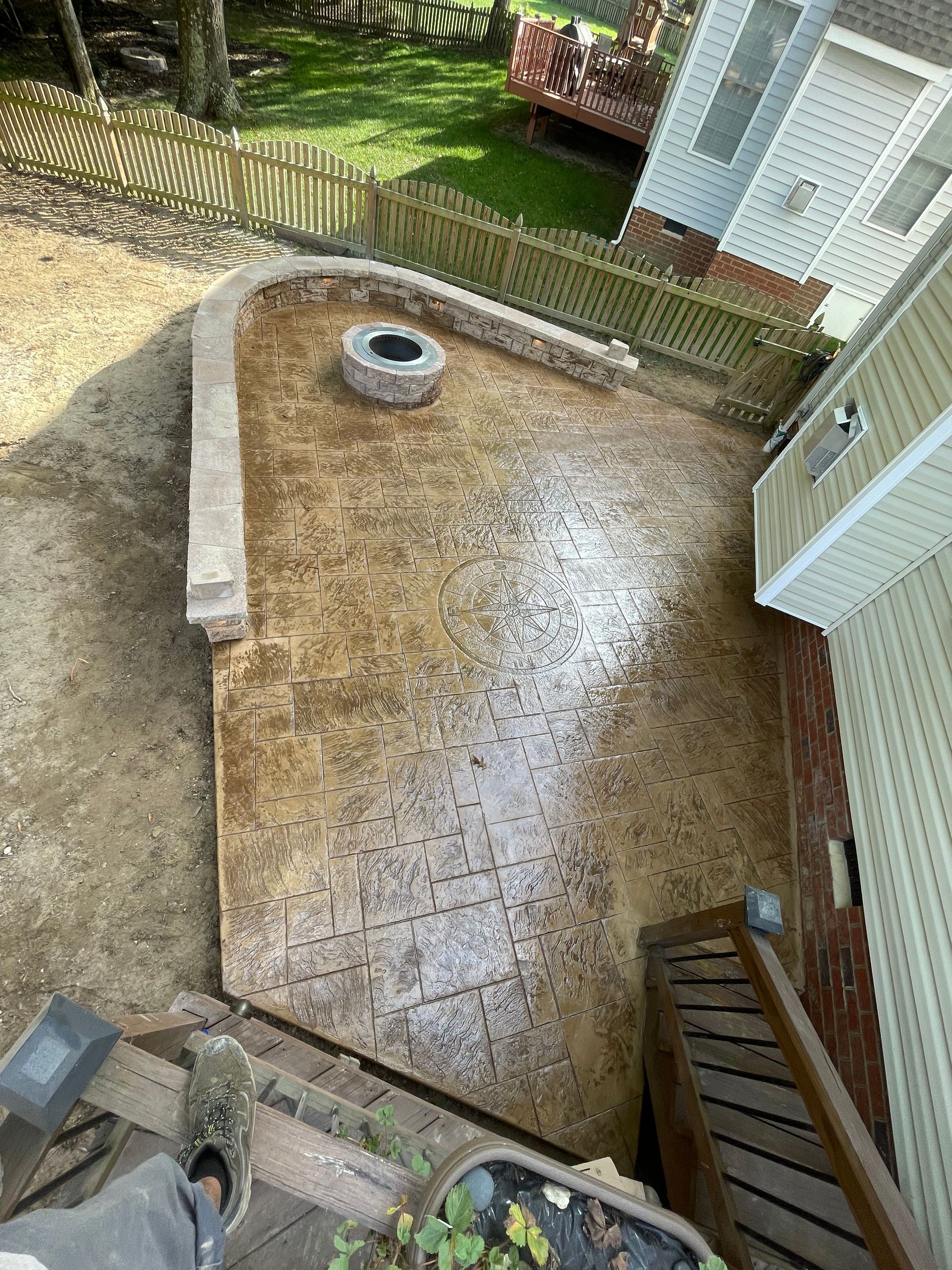 An aerial view of a concrete patio with a fire pit in the middle of it.
