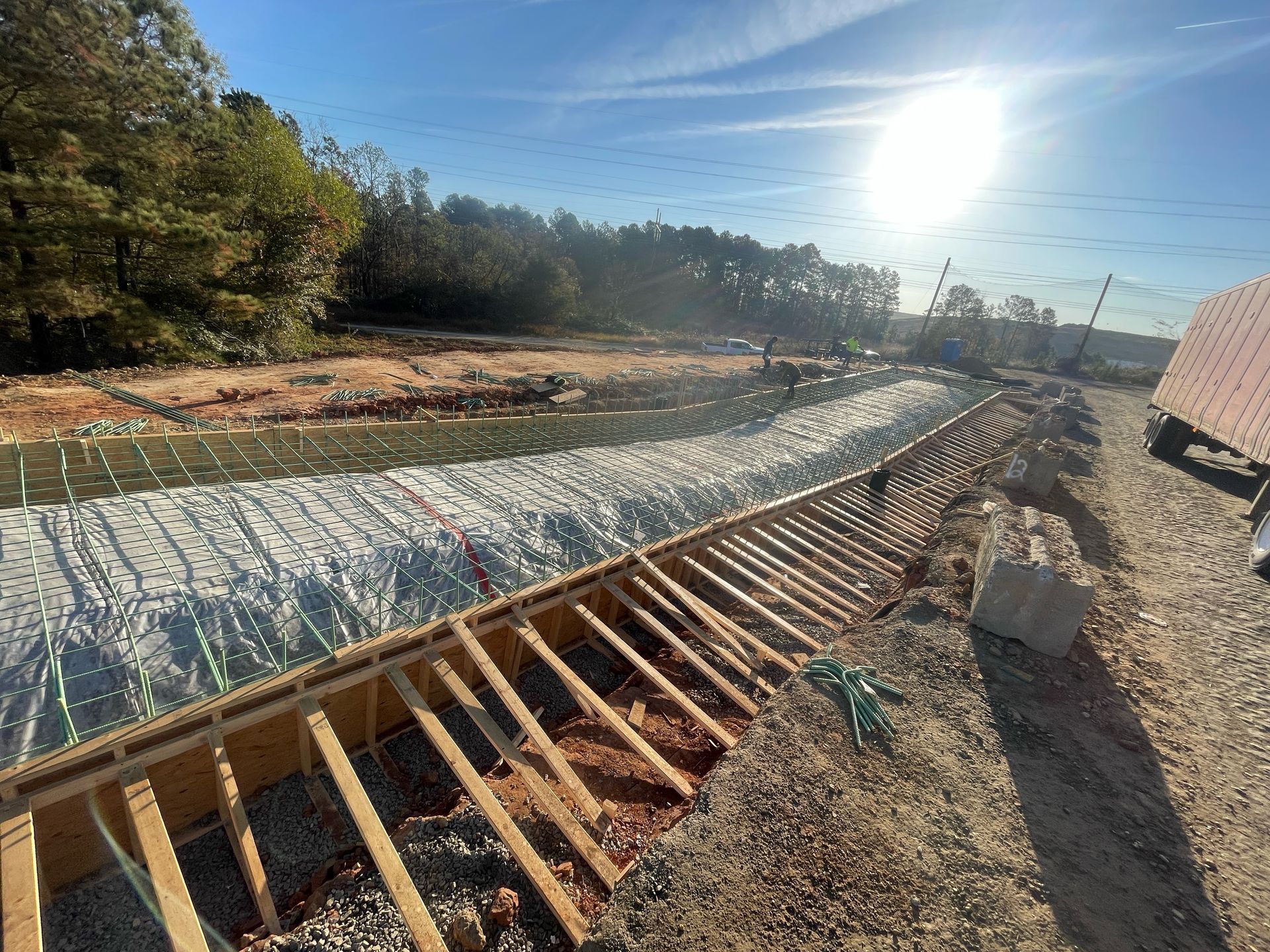 A construction site with a river in the background and a fence in the foreground.