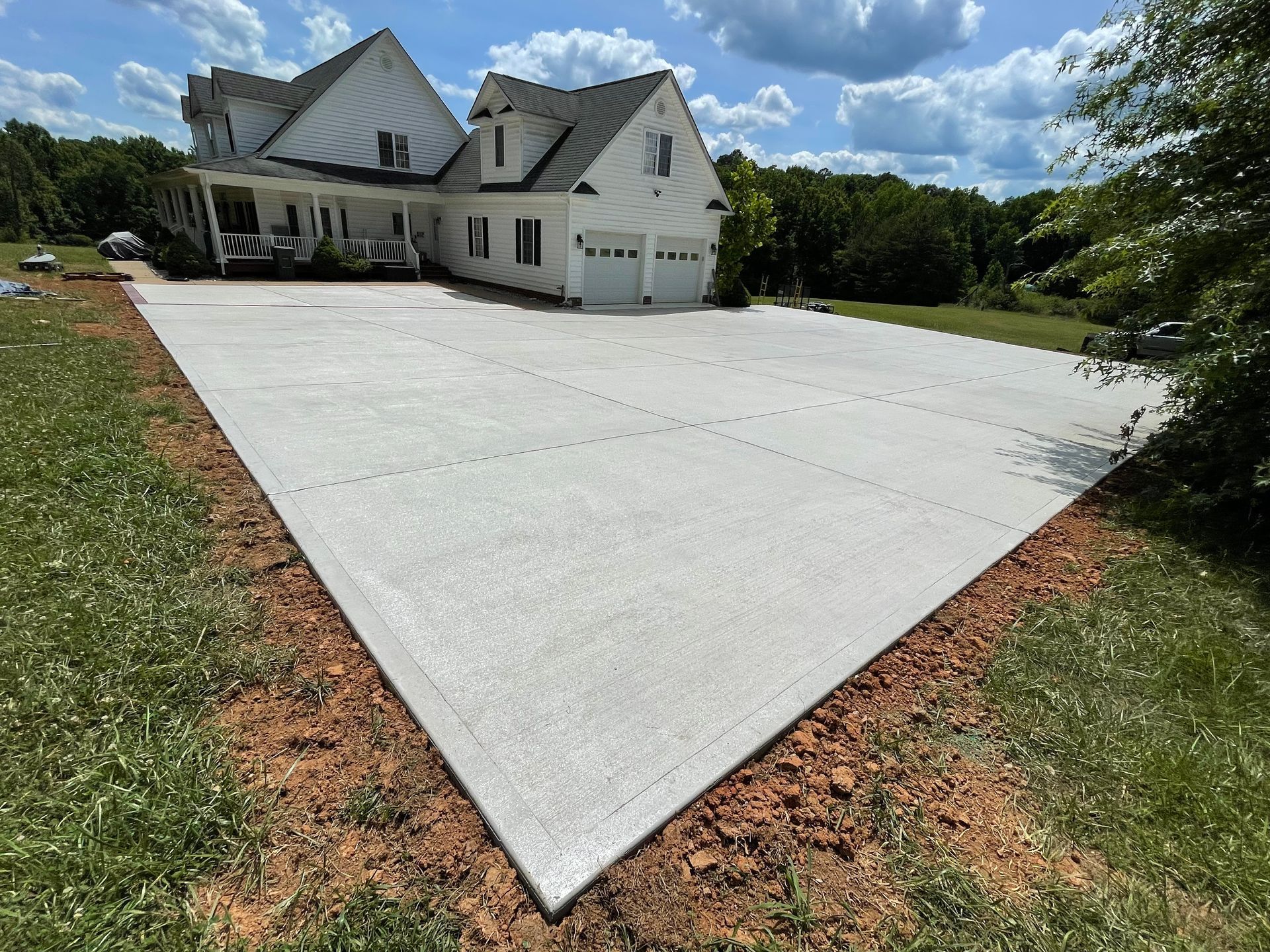 A large white house with a concrete driveway in front of it.