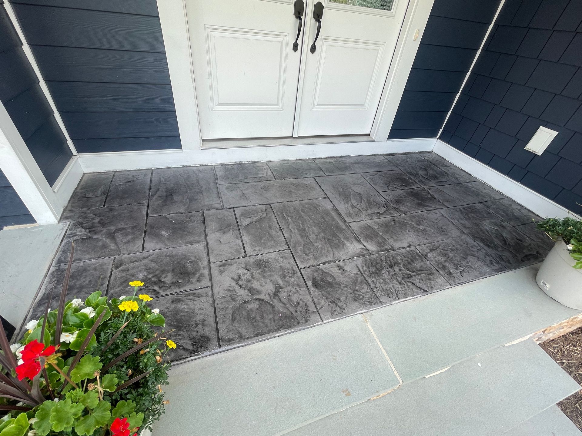A concrete porch with a planter of flowers in front of it
