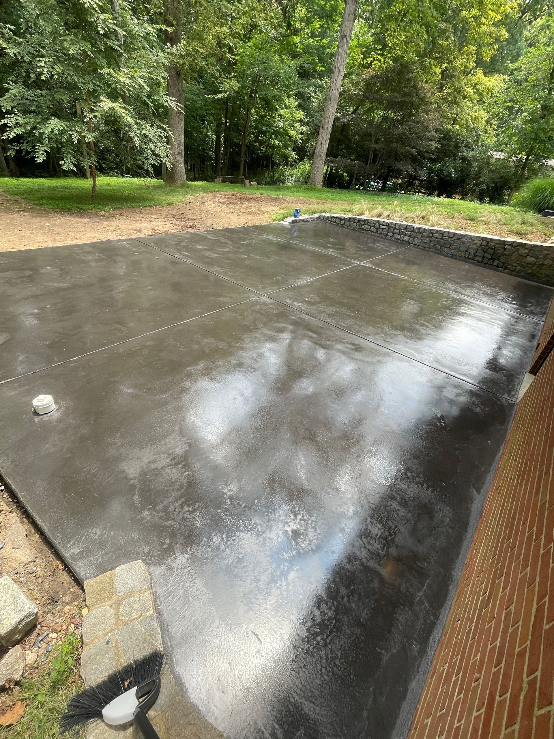 A concrete driveway in a backyard with trees in the background.