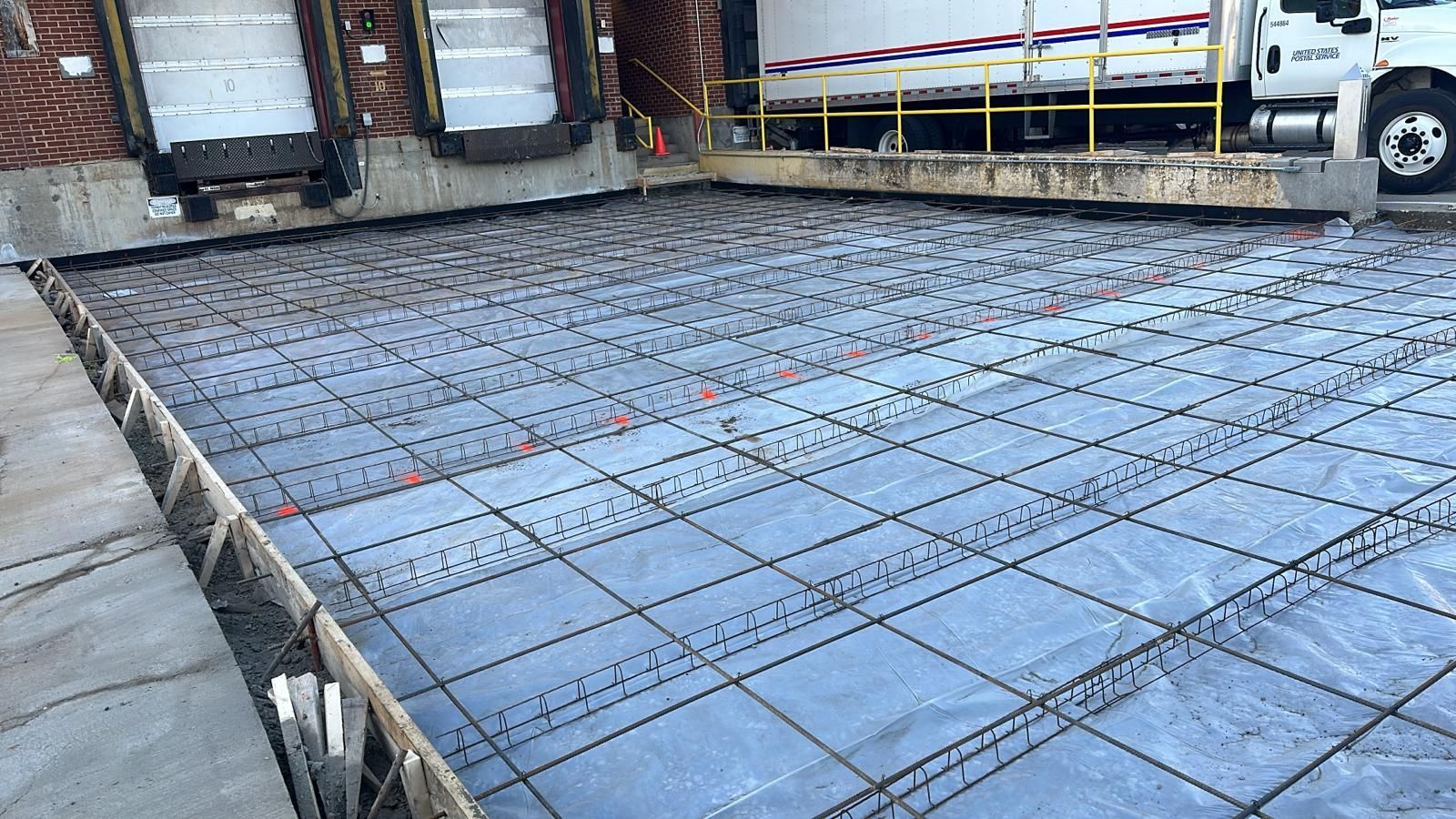 Reinforced concrete wall under construction with exposed rebar.