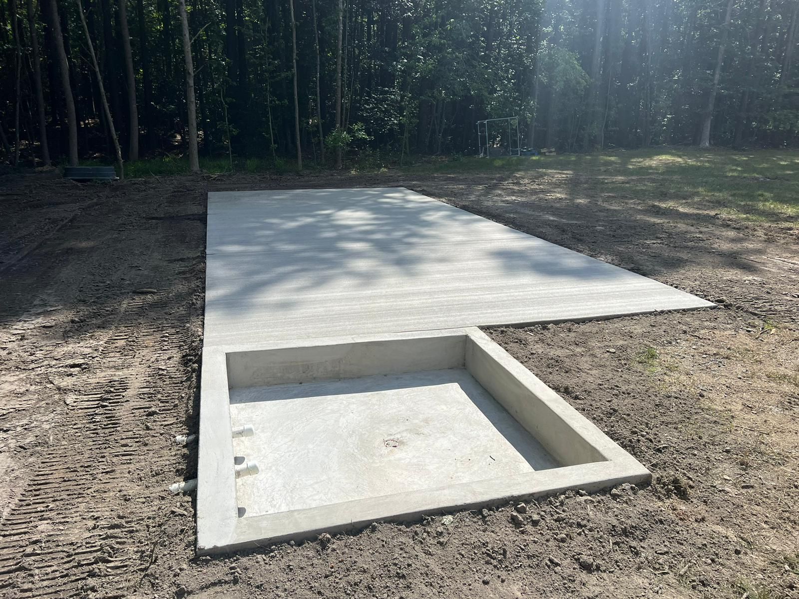 A large concrete slab is sitting in the middle of a dirt field.