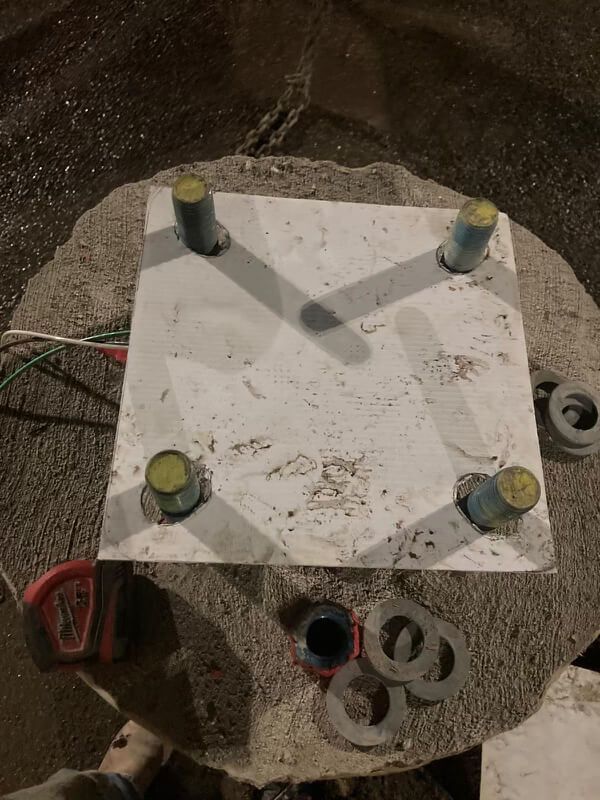 A square piece of metal is sitting on top of a concrete table.
