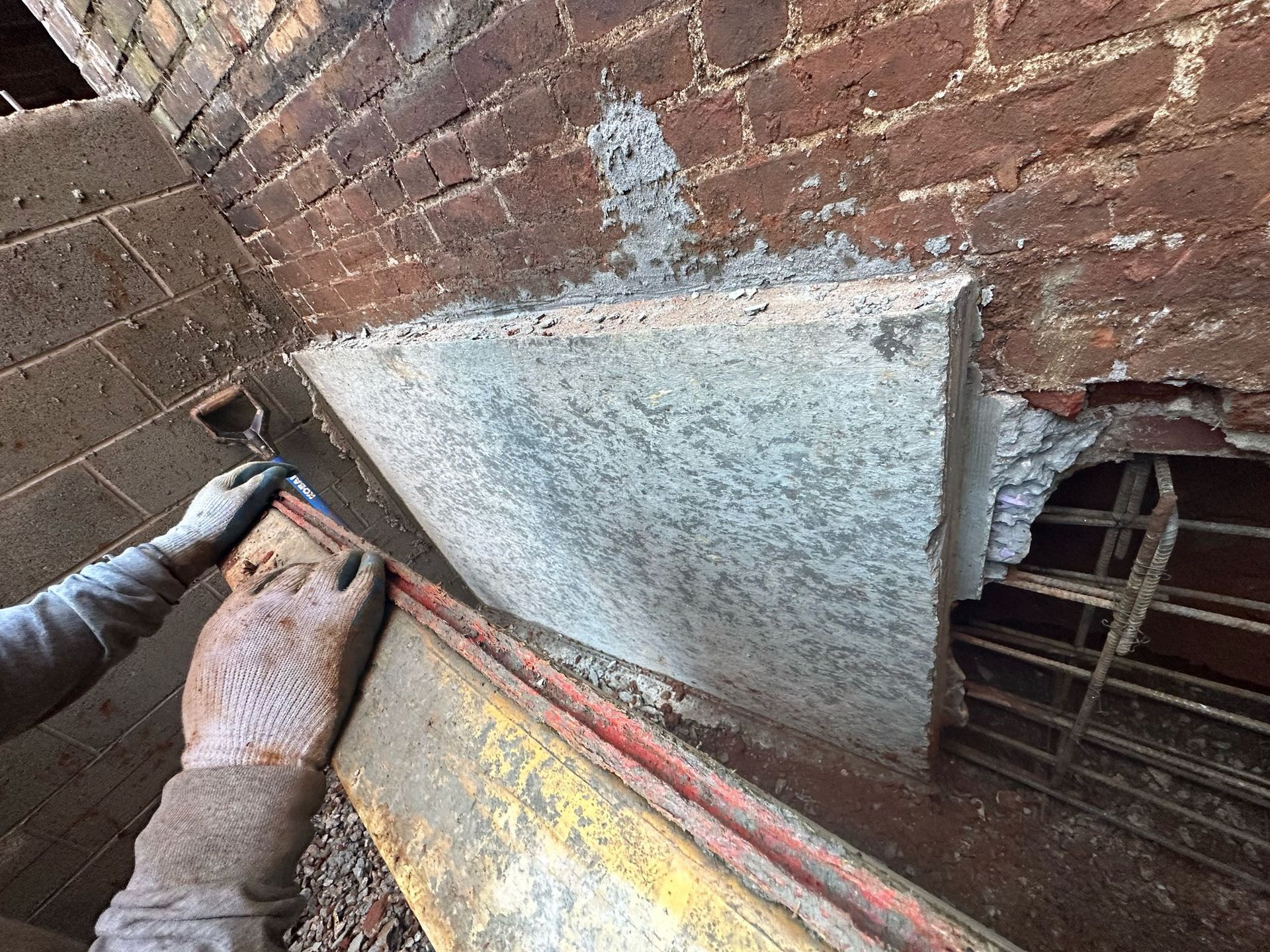A person is painting a brick wall with a brush.