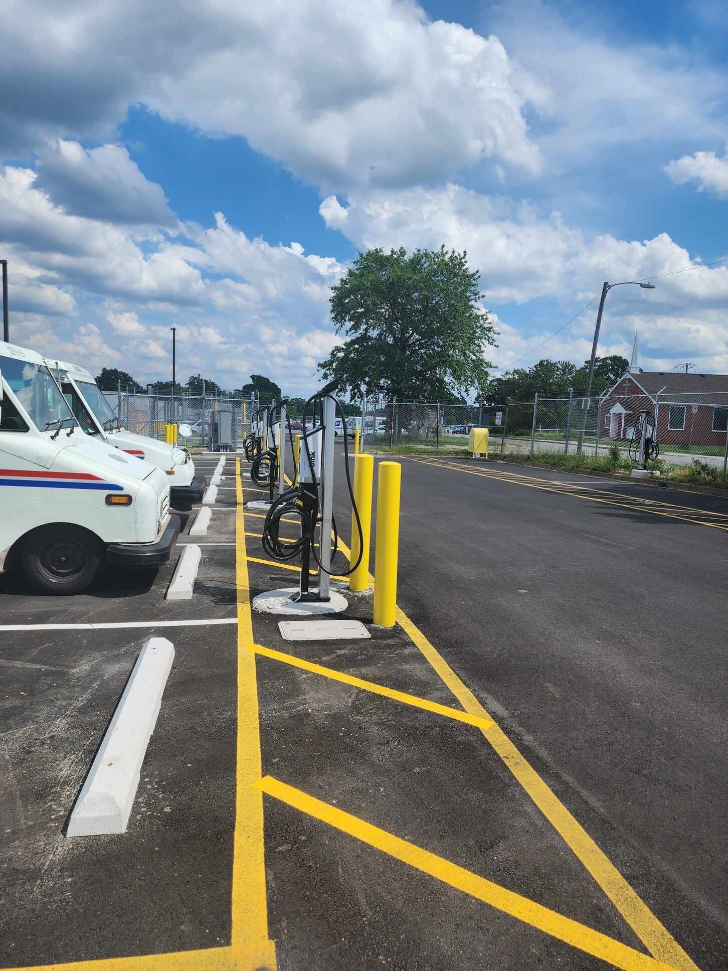 A row of mail trucks are parked in a parking lot