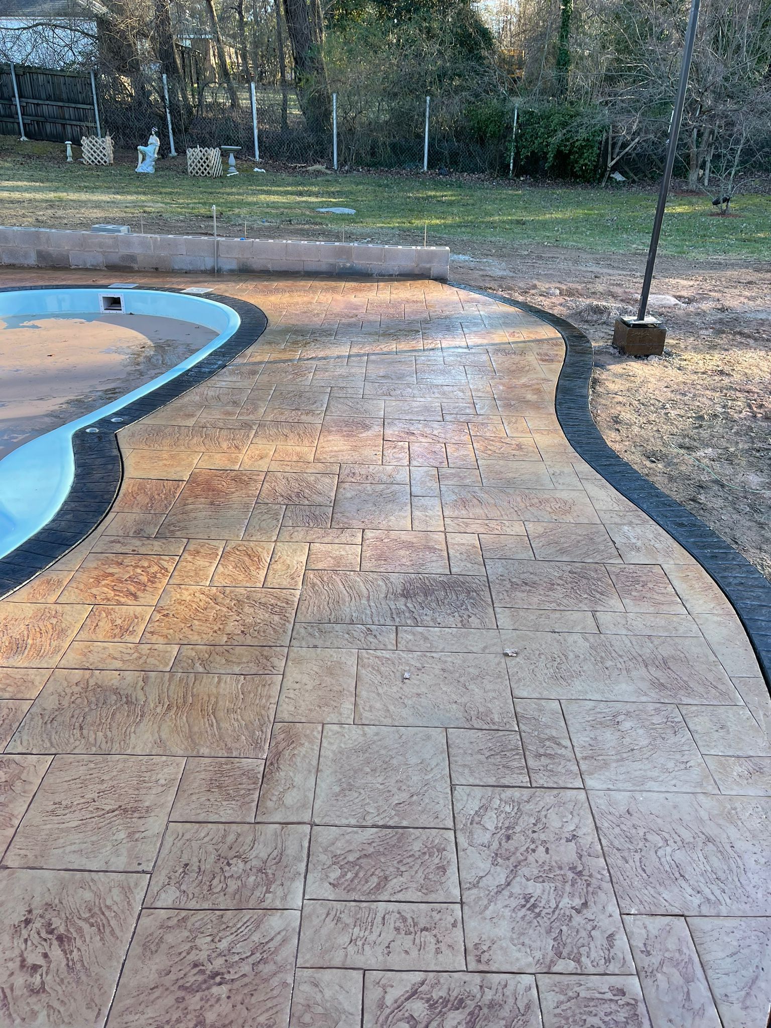 A concrete walkway leading to a pool in a backyard.