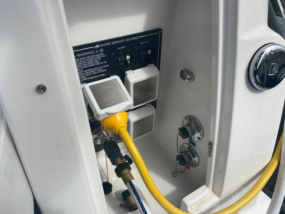 A yellow hose is attached to a white box on a boat