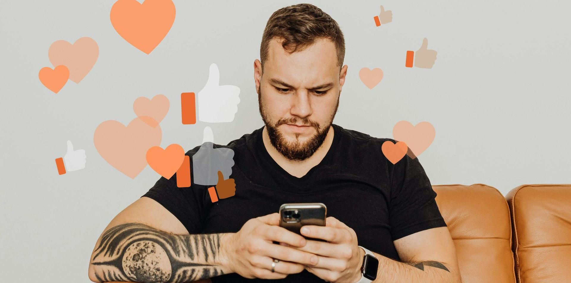 Um homem está sentado no sofá olhando para o celular.