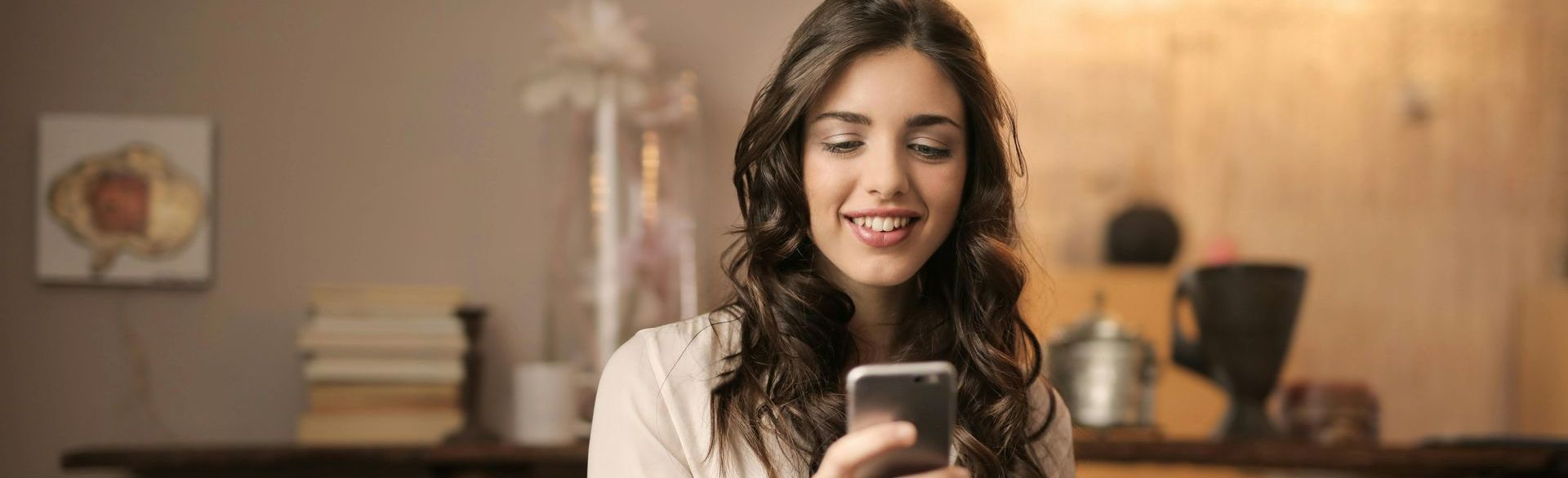 Uma mulher sorri enquanto olha para o celular.