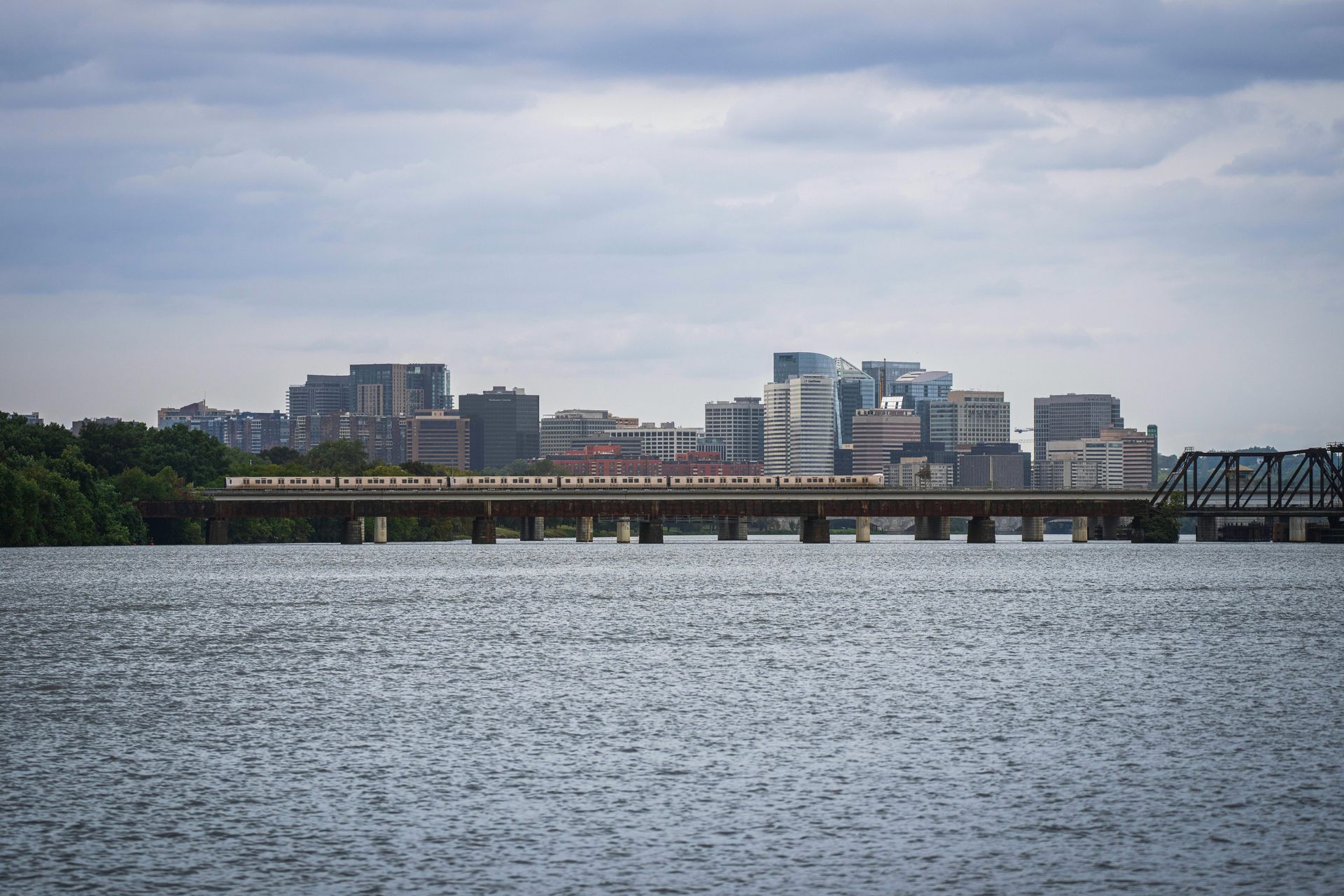 A bridge over a body of water with the Arlington Virginia skyline in the background.