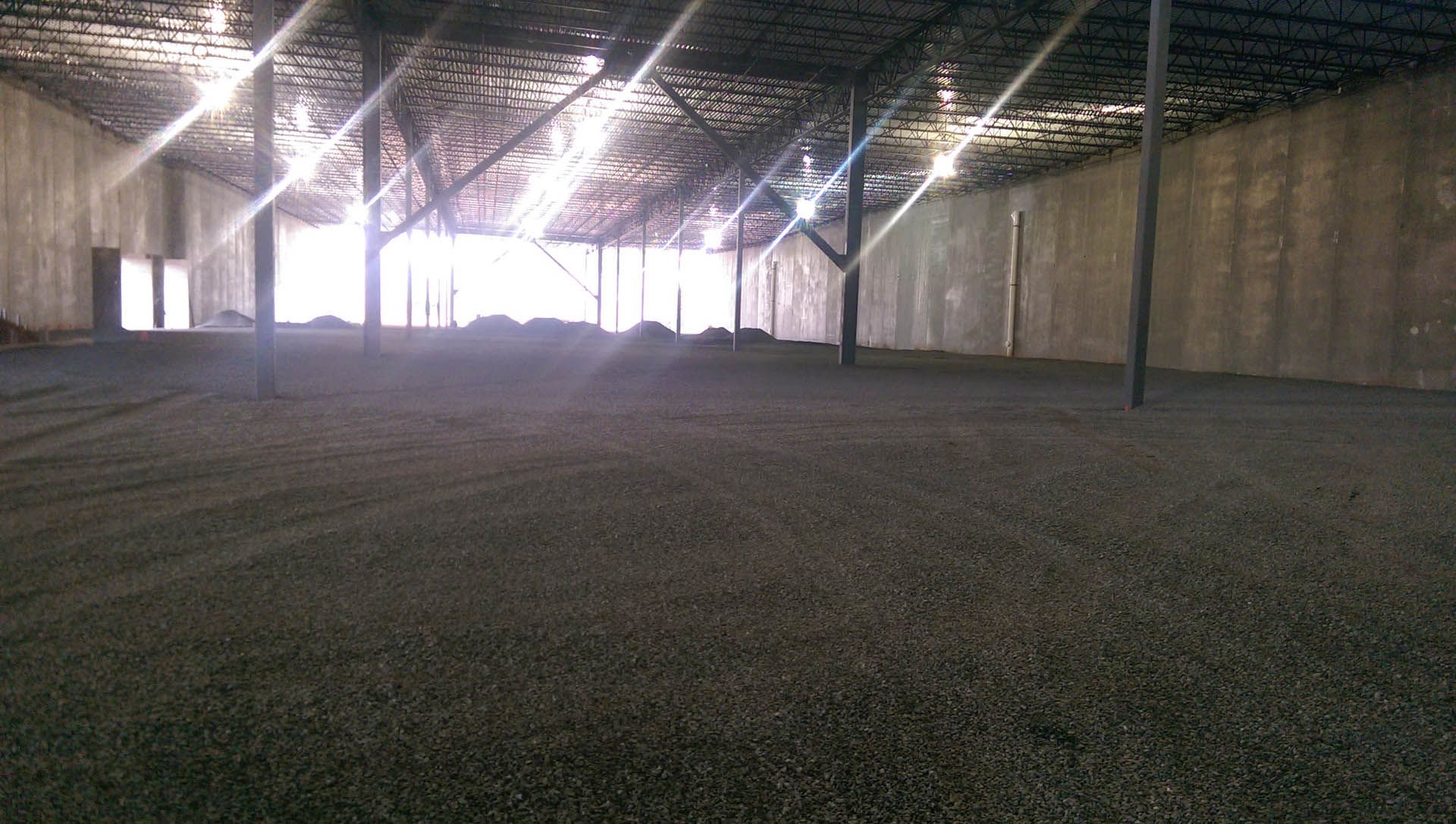 Dark interior of a building filled with a dark material, with sunlight streaming in from the opening.