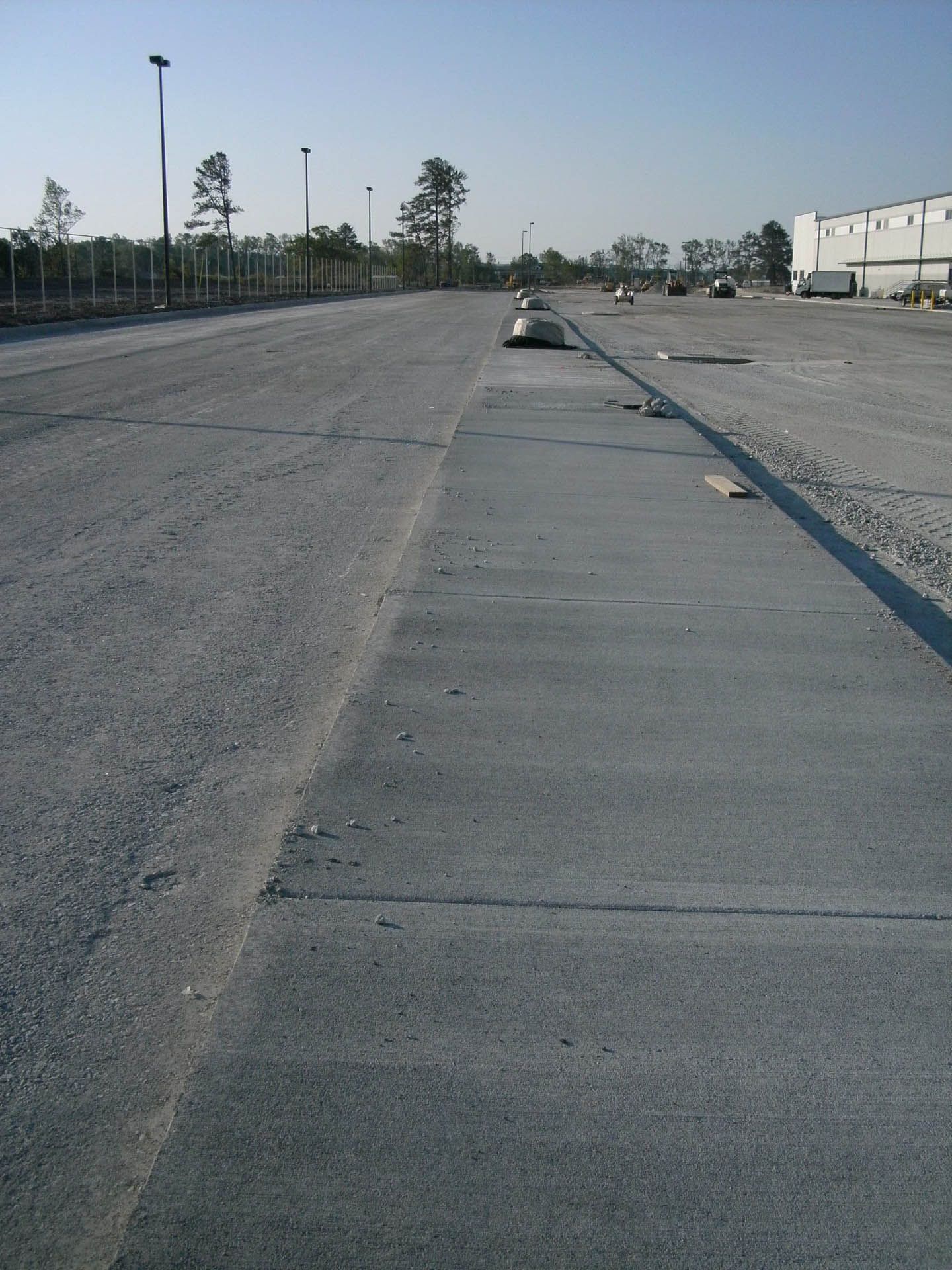 Gravel and concrete road leading to industrial buildings on a sunny day.