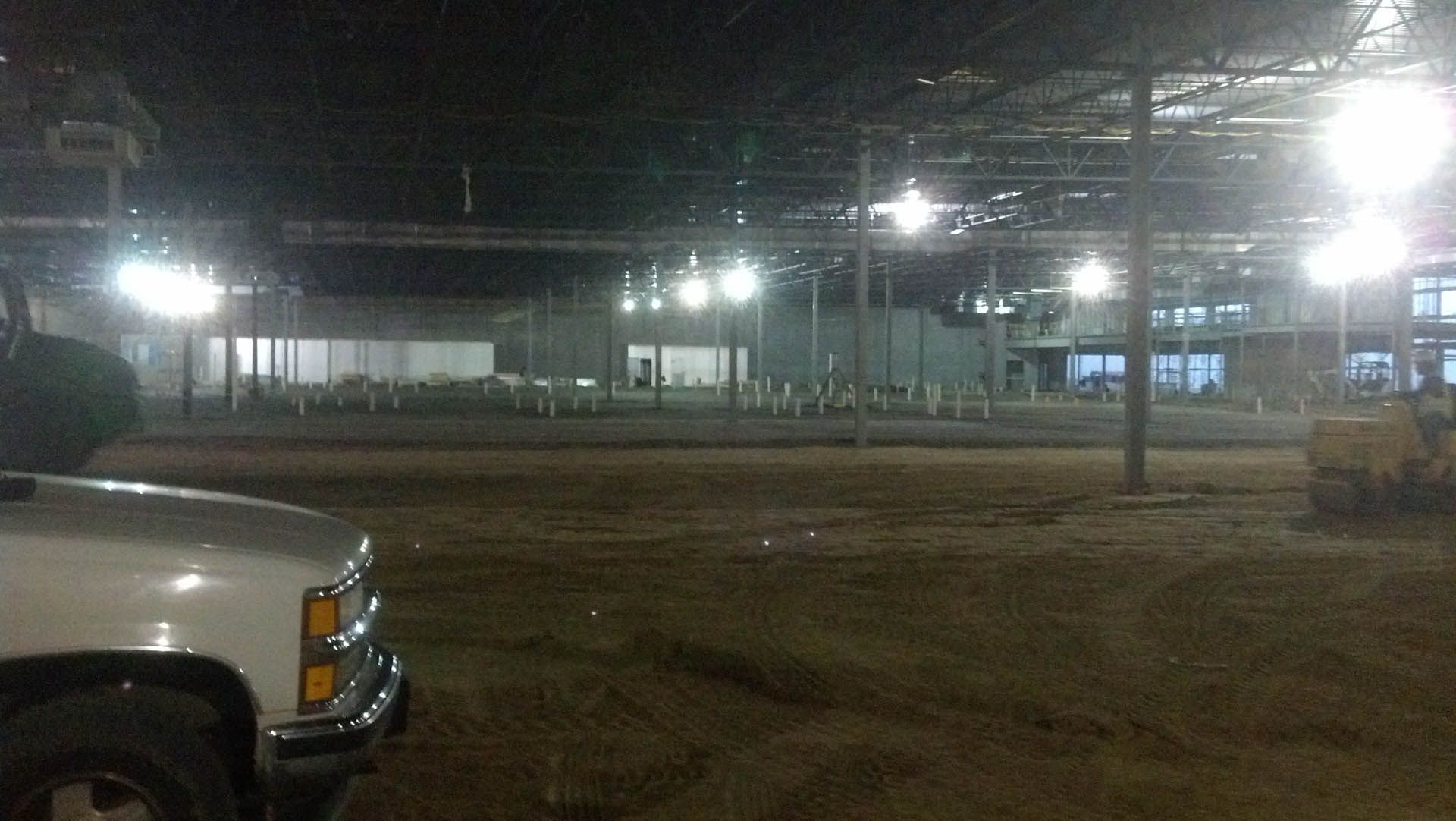A nighttime view of a construction site with bright lights and a truck in the foreground.
