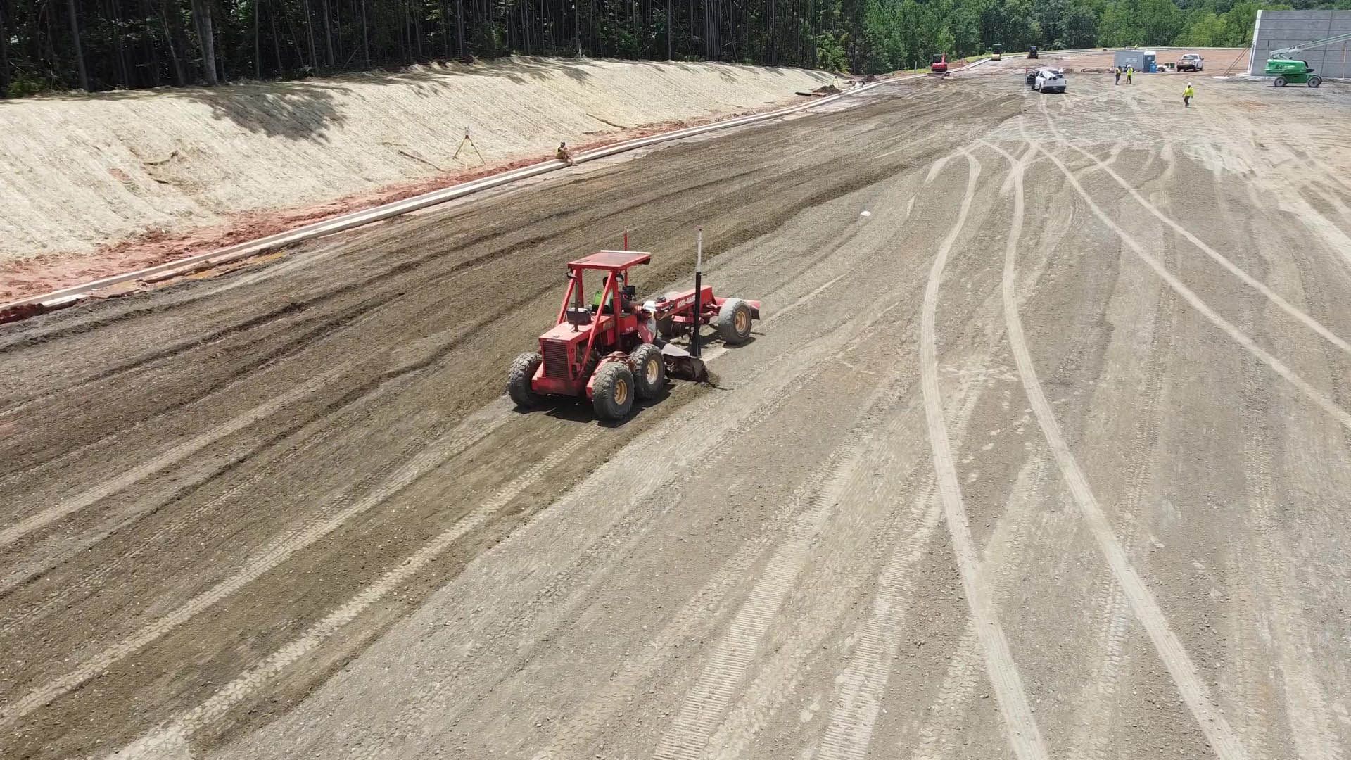 Red tractor grading earth on a construction site.