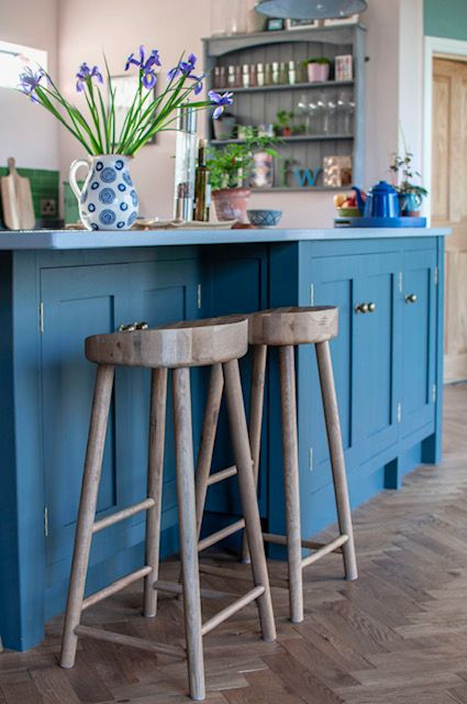 Heritage interior designed kitchen, with a blue island and wooden stools.