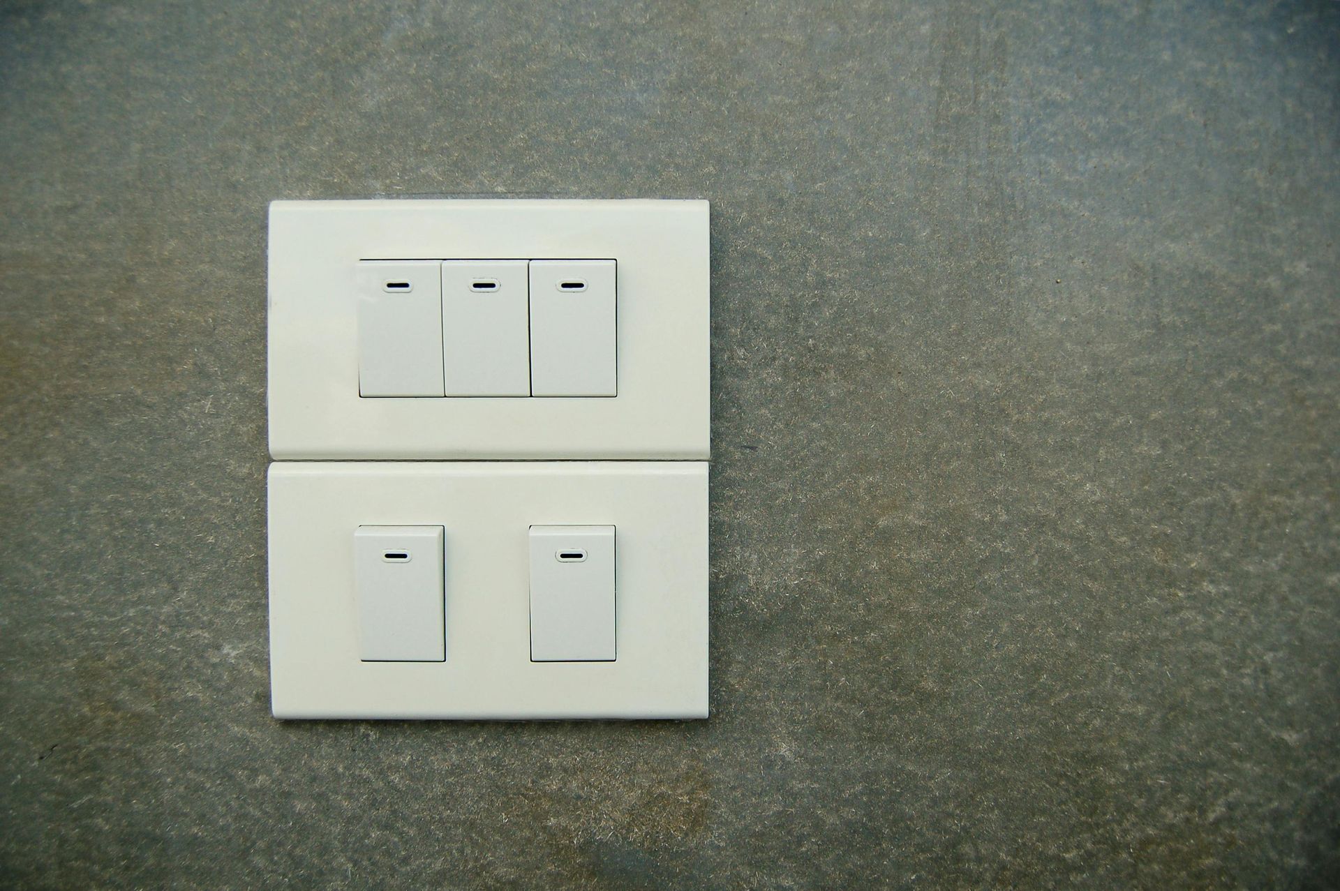 White light switches on gray wall.