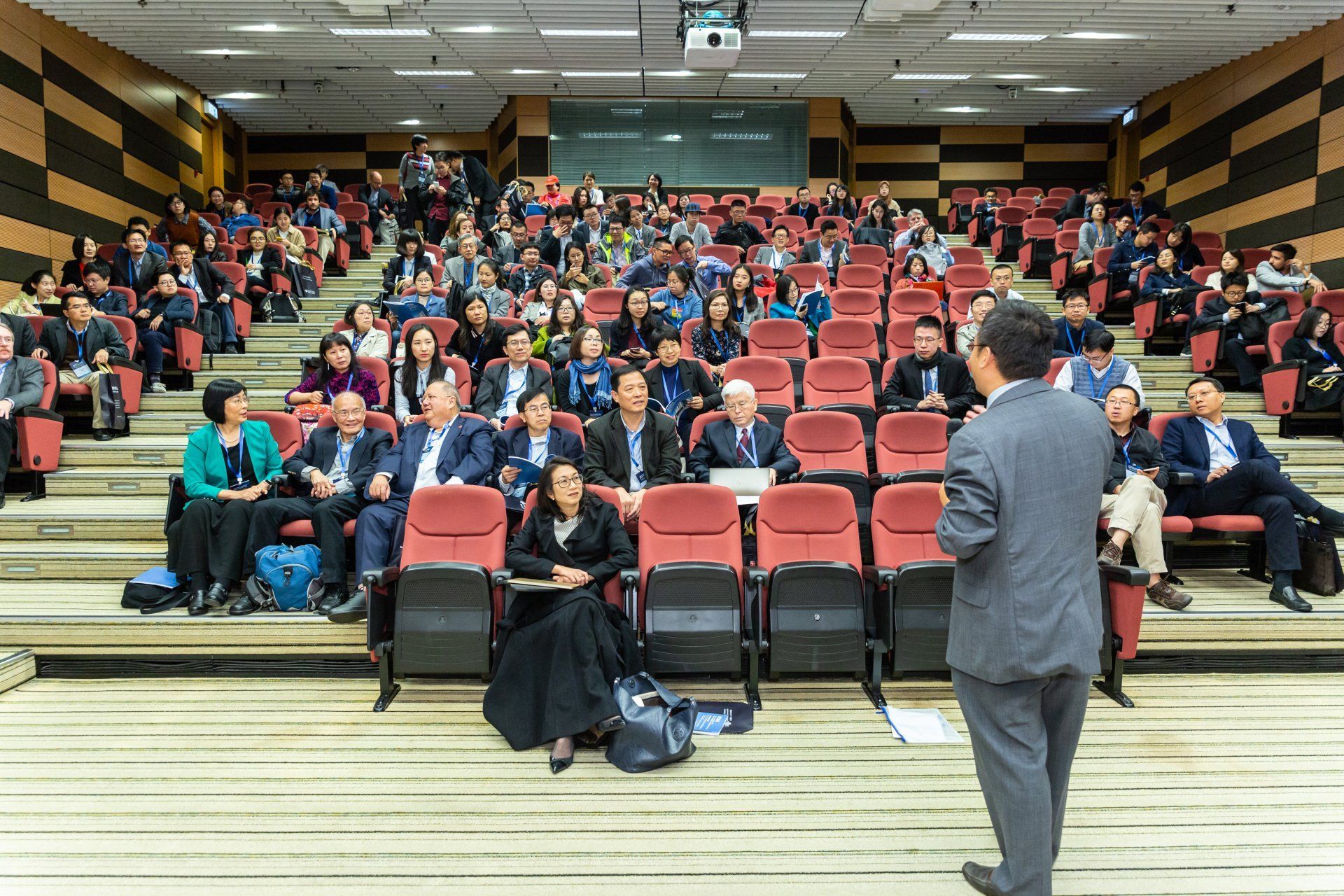 A man is giving a presentation to a large group of people in an auditorium.