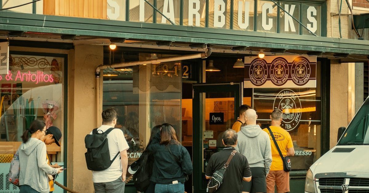 A group of people are standing outside of a starbucks coffee shop.
