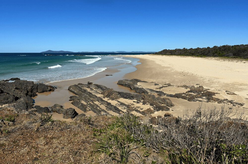 A Beach With a Lot of Rocks on It and a Blue Sky — Mackie's Concrete Pumping In Hallidays Point, NSW