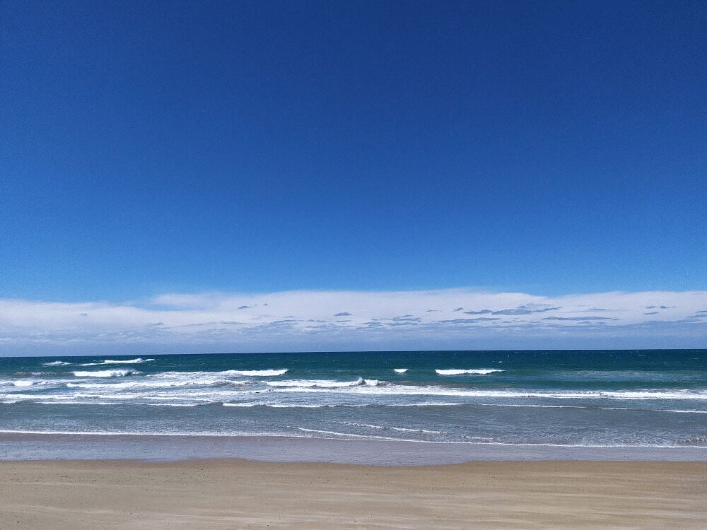 A Beach With a Blue Sky and Waves Coming in — Mackie's Concrete Pumping In Old Bar, NSW