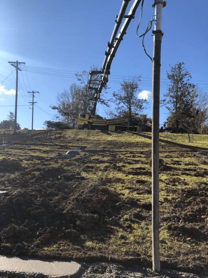 A Crane is Lifting a Pole in a Field — Mackie's Concrete Pumping In Tuncurry, NSW