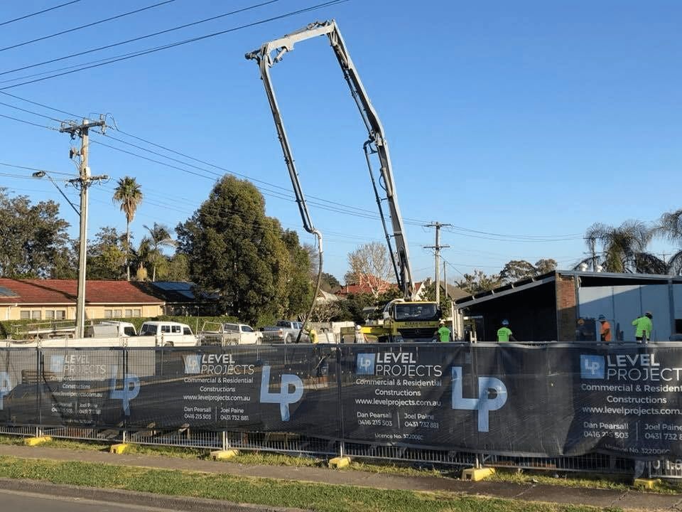 A Construction Site With a Fence and a Crane — Mackie's Concrete Pumping In Tuncurry, NSW