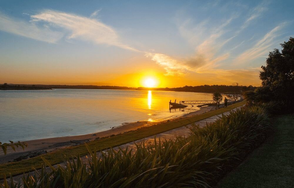 A Sunset Over a Lake With a Boat in the Water — Mackie's Concrete Pumping In Taree, NSW
