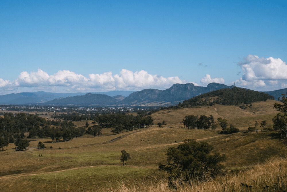 A View of a Grassy Hillside With Mountains in the Background on a Sunny Day — Mackie's Concrete Pumping In Gloucester, NSW