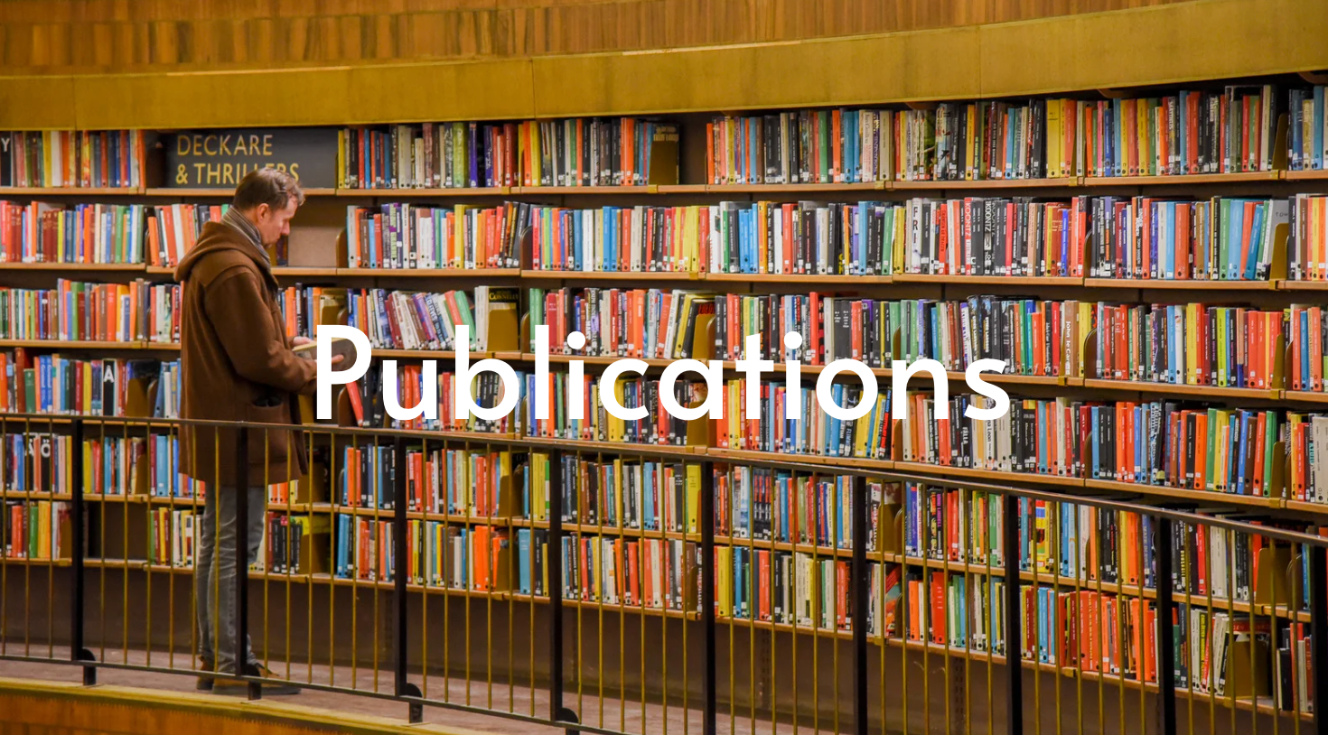 Man browsing books in a library. Many colorful books on shelves.