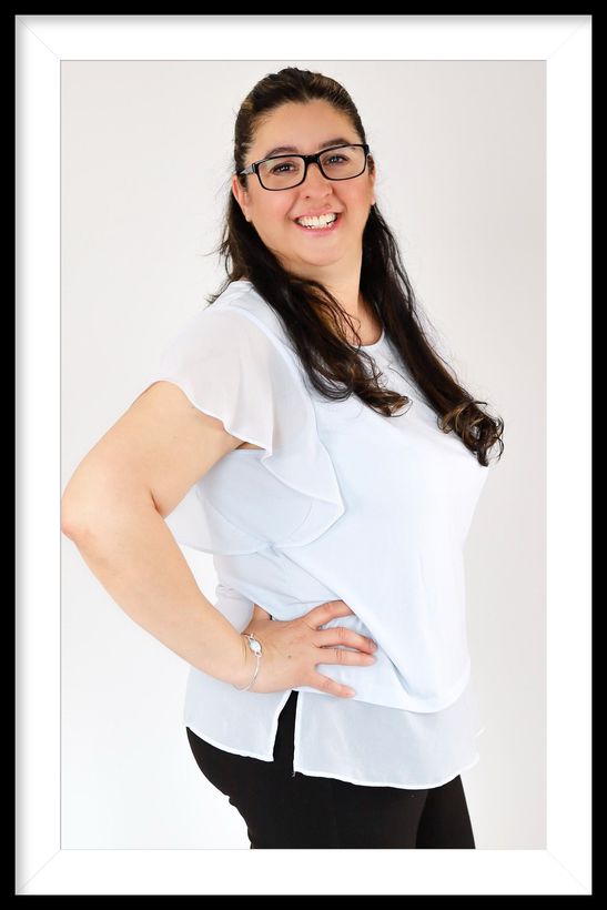 A vase of white tulips next to a cup of coffee on a table.