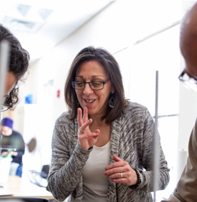Woman in glasses gesturing while speaking in a bright office meeting