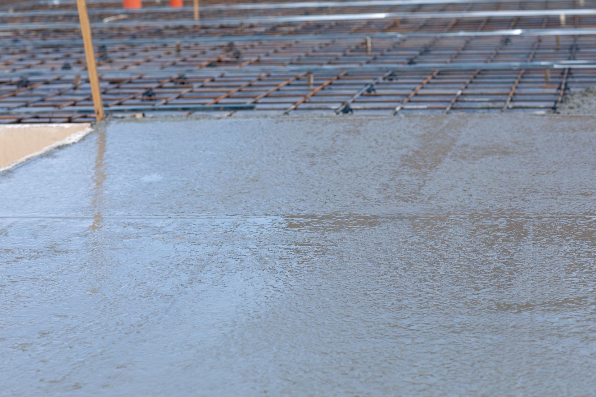 Freshly poured concrete surface with rebar grid in the background.