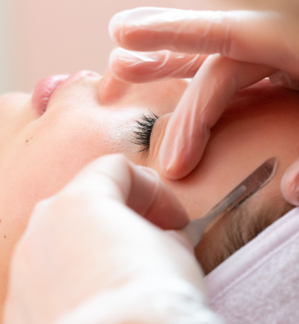 A woman is getting her eyebrows shaved with a razor