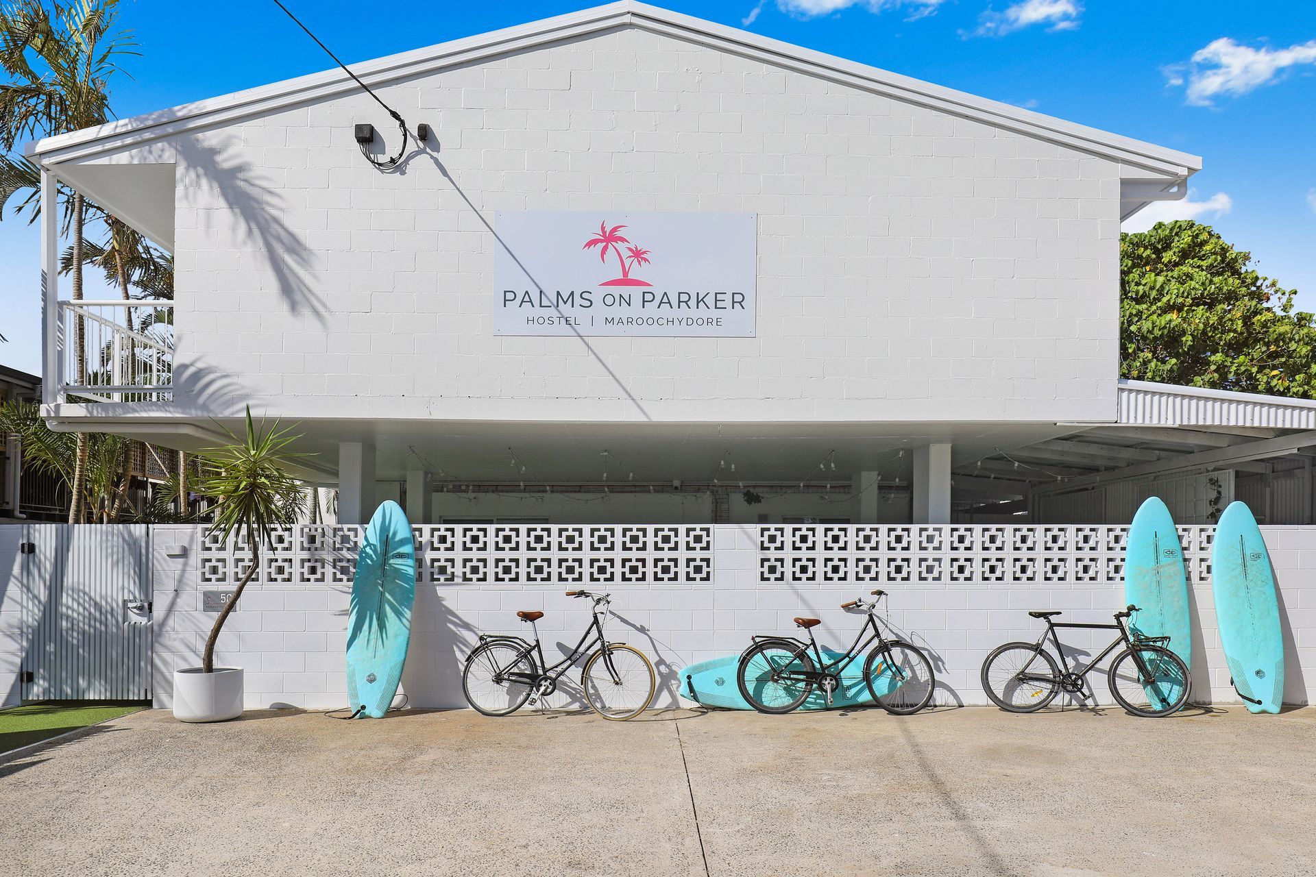 A white building with surfboards and bicycles parked in front of it.