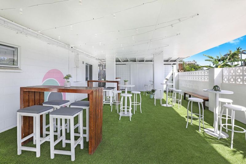 A patio with tables and stools on a lush green lawn.