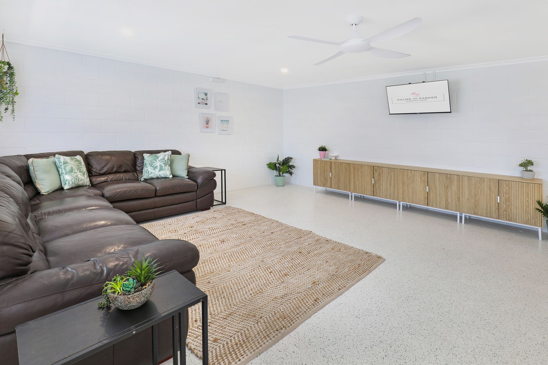 A living room with a couch , table , rug and ceiling fan.
